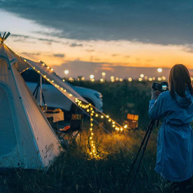 Outdoor camping setup illuminated by BLACKDEER Solar String Lights Led under a sunset sky.