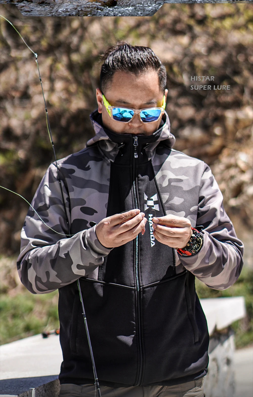 Man in camouflage jacket and reflective sunglasses holding a fishing rod, with 'Huk' branding visible.
