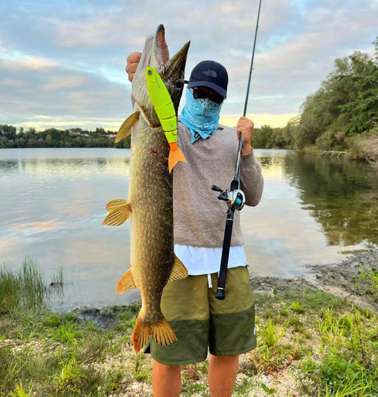 Angler holding a large fish caught with TSUYOKI Balam Swimbait Floating/Sinking 245mm near a lake.