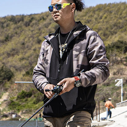 Man in camouflage jacket holding a fishing rod with a scenic background